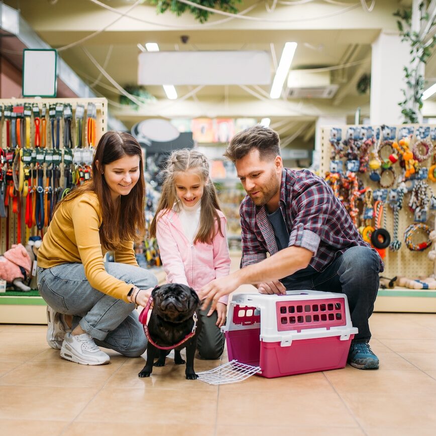 Family buying supplies for little puppy in petshop. Father, mother and dauther chooses accessories for dog in pet shop